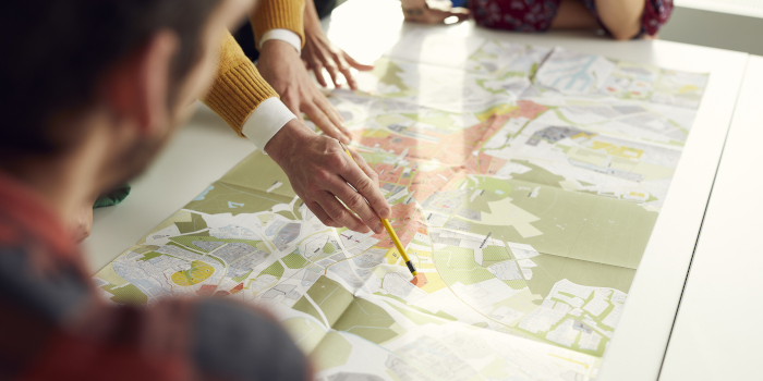 Stadtplan auf Tisch, Frau erklärt dazu 
