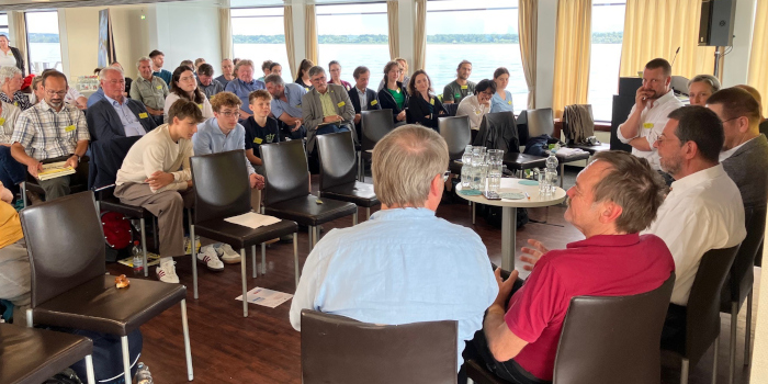 Tagung der Umweltakademie, Referierende im Vordergrund, Teilnehmende im Hintergrund