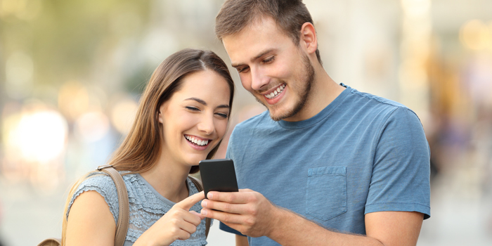 Frau und Mann schauen lachend in ihr Smartphone (Foto: © Antonioguillem/Fotolia.com)