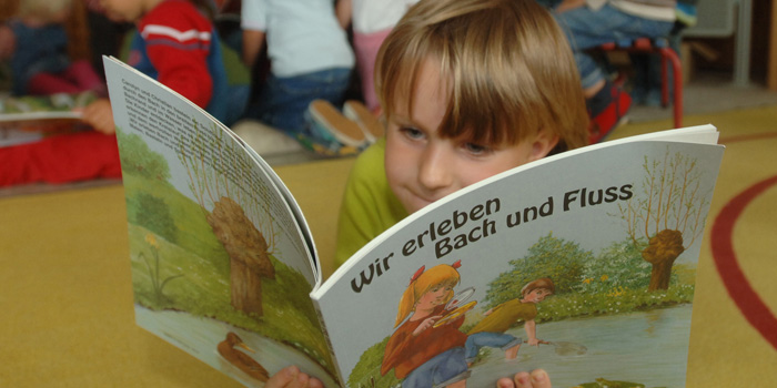 Ein Kind liest ein Buch über Flüsse und Bäche. (Foto: © Werner Kuhnle)